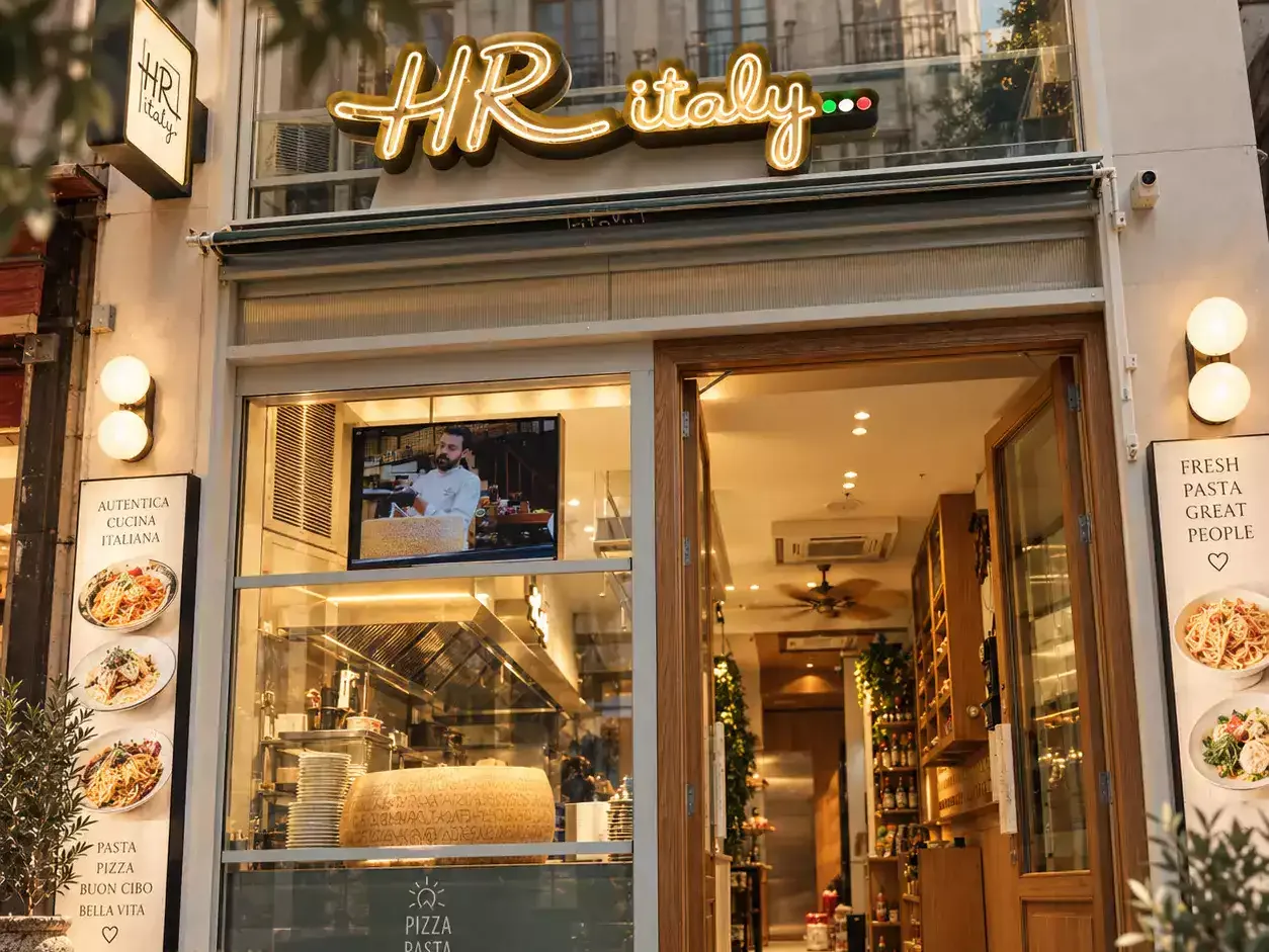 L'entrée de HR Italy Eminönü : l'enseigne lumineuse, la porte ouverte et la cuisine derrière la vitrine