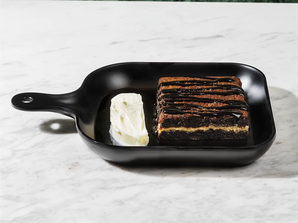 Brownie mit weißer Schokolade von HR Italy: Brownie in einer schwarzen Servierpfanne mit Eis