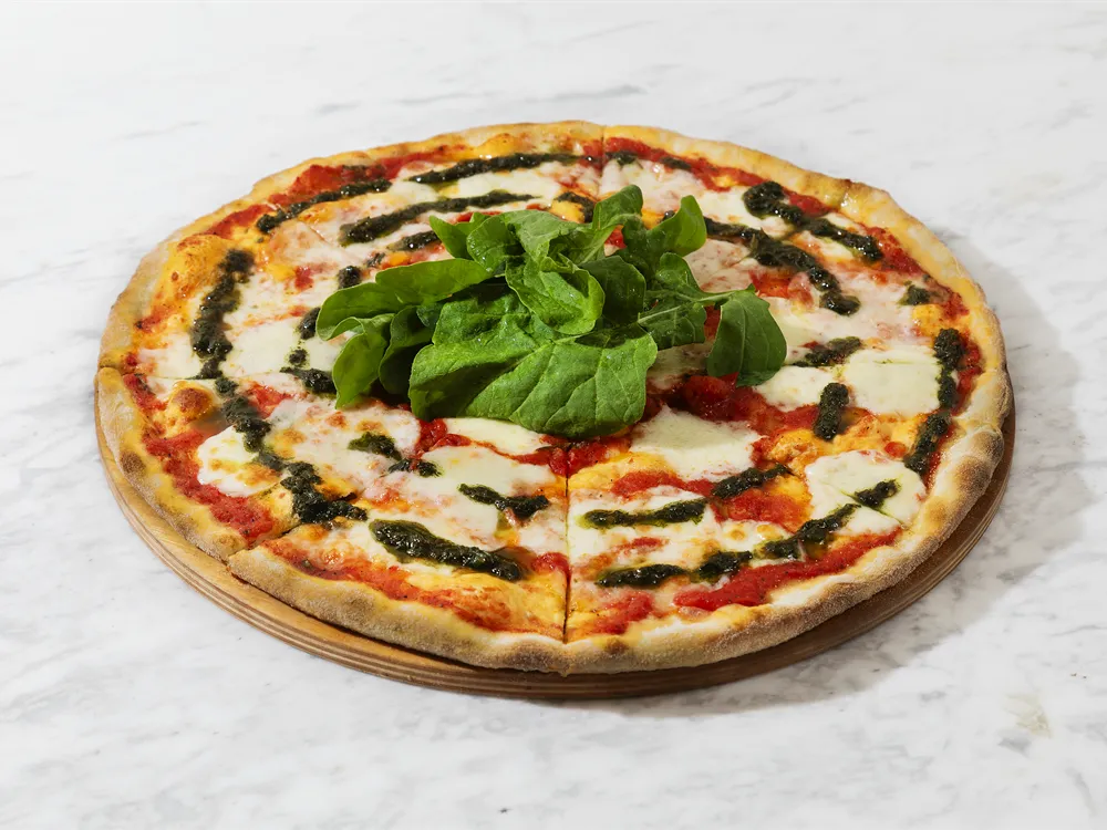 Margherita Pizza von HR Italy: Margherita mit Pesto und grünen Blättern auf einem Holzbrett