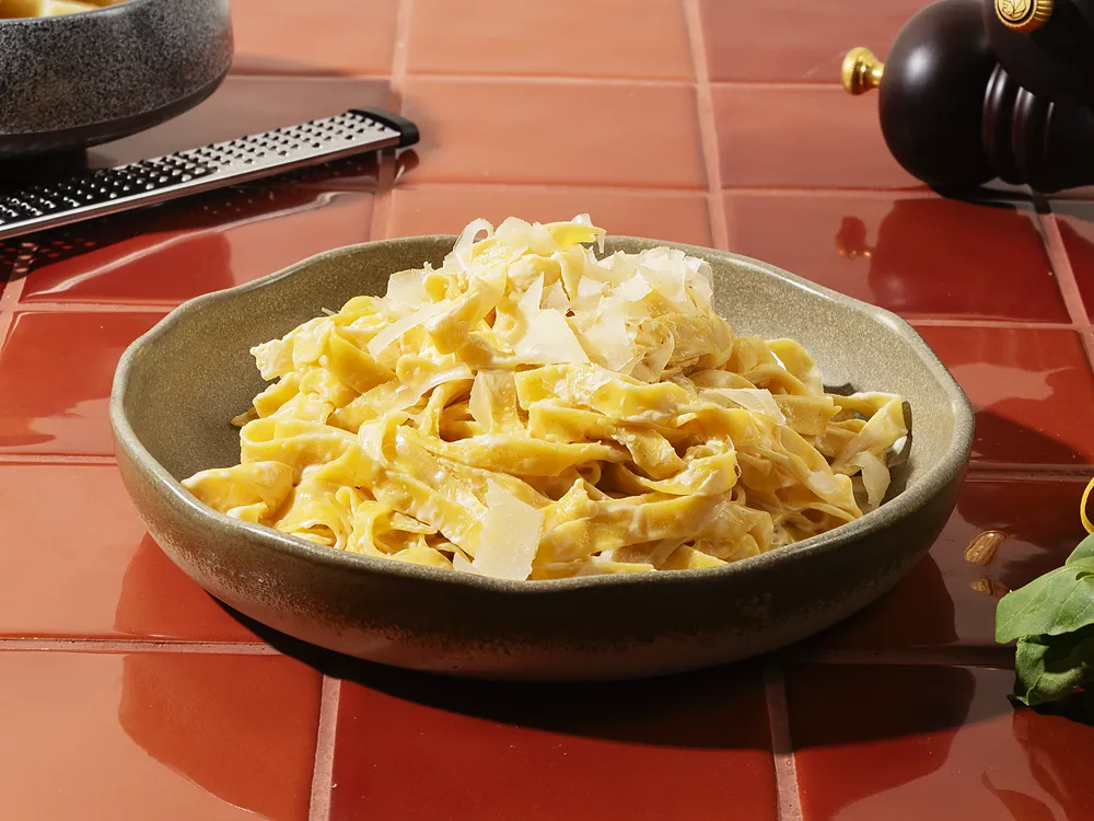 Fettuccine mit Parmesanrahm von HR Italy: ein Teller frische Fettuccine in Parmesan-Sahnesoße auf Terrakottafliesen