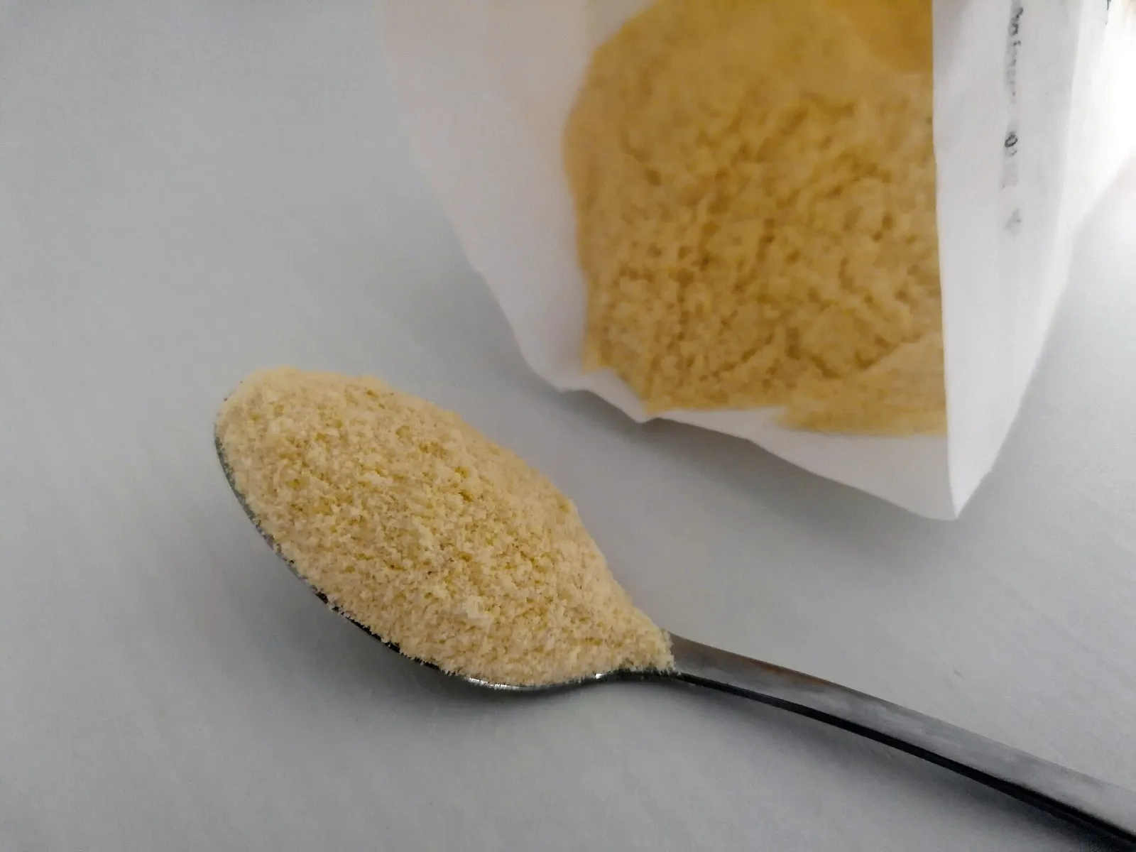 Semoule de blé dur jaune pâle et granuleuse dans une cuillère et un sachet en papier